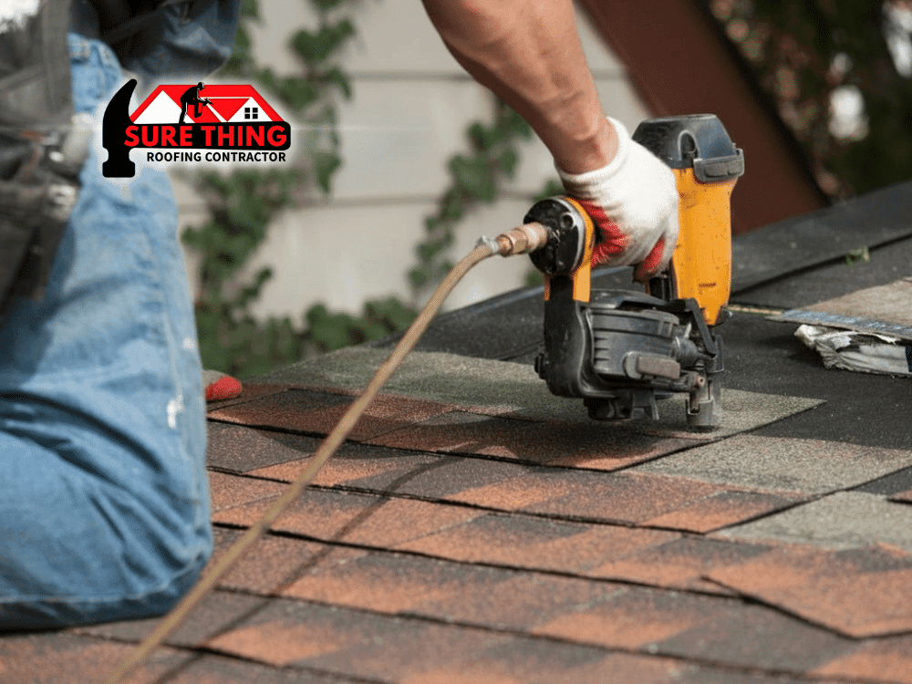 Roofer installing shingles on a roof in Georgia using a pneumatic nail gun.